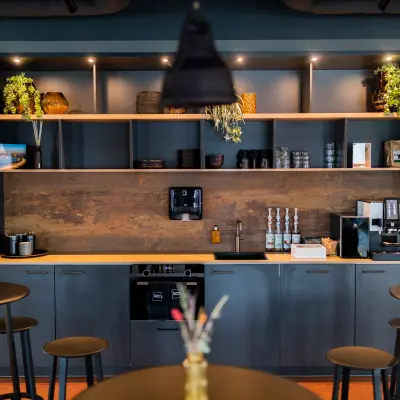 Furnished office space at Wilhelminaplein 1-40 in Rotterdam Kop van Zuid features a modern pantry area with sleek shelves, coffee machines, and stylish decor—ideal for a seamless office space rental experience.