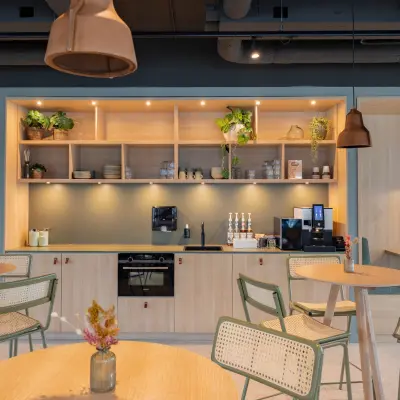 Furnished office space with modern tables and greenery, available for office space rental at Wilhelminaplein 1-40 in Rotterdam Kop van Zuid.