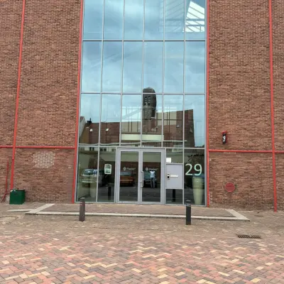 Exterior view of the office building at Scheepsbouwweg 29, Rotterdam Waalhaven, showcasing a modern glass entrance suitable for those seeking office space rental.