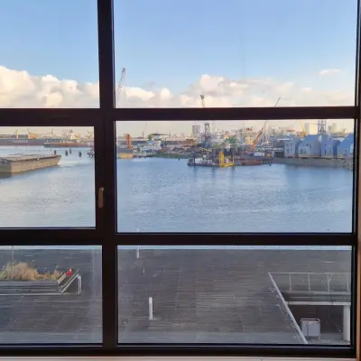 Bright office view of the Rotterdam Waalhaven port through large windows, ideal for those seeking office space rental with a scenic backdrop.