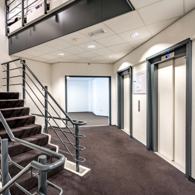 Interior view of a modern office building at Overschieseweg 304-332, Schiedam, featuring an open area with elevators and a staircase, ideal for efficient office space rental.
