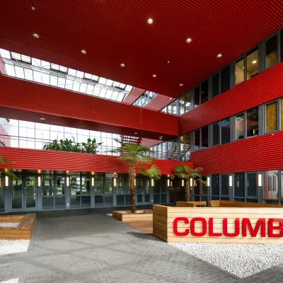 Modern office entrance with red and grey architectural design and skylight in Schiphol Airport for office space rental.