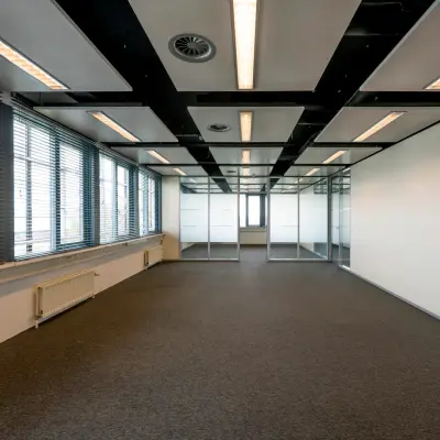 Spacious, unfurnished office space at Schiphol Airport, featuring large windows and modern lighting, available for rent.