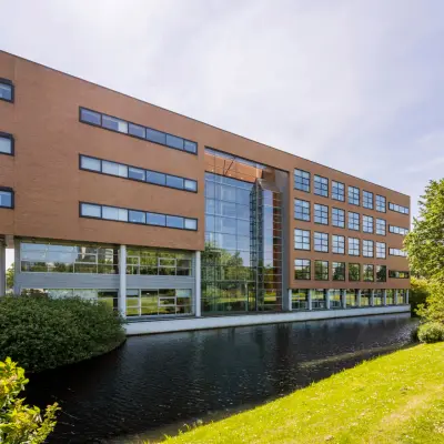 Exterior view of an office building at Boeing Avenue 1-19, Schiphol Rijk, ideal for office space rental with a modern facade next to a serene water body.