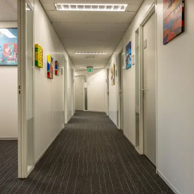 Hallway of an office for rent at Curieweg 9, Spijkenisse, showcasing framed artwork on walls and a modern ceiling. Ideal for those seeking office space rental.