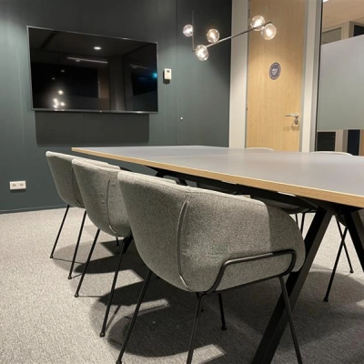 Modern conference room with a sleek table, comfortable chairs, and a wall-mounted TV, suitable for office space rental in The Hague Center at Alexanderveld 5-9.