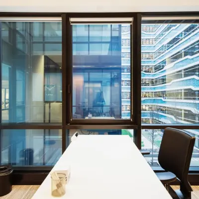 Bright office space at Anna van Buerenplein 41 in The Hague Center, featuring a large window with a modern city view, available for rent. Includes a sleek table and office chair.