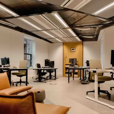 Spacious office with several desks and chairs, featuring modern lighting and a relaxed seating area, ideal for anyone looking to rent office space in The Hague Center.