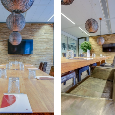 Spacious conference room at Kalvermarkt 53, The Hague Center, featuring a large wooden table, leather chairs, and decorative lighting. Ideal office space rental for meetings. TV mounted on textured wall.
