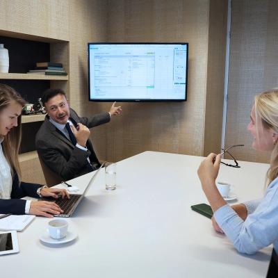 Colleagues in The Hague Center discuss project details in a modern conference room at Koninginnegracht 19. Ideal office space rental for collaborative meetings.