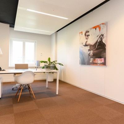 Bright office space with a large desk, modern chair, and artwork on the wall at Koninginnegracht 19, ideal for rent office space in The Hague Center.