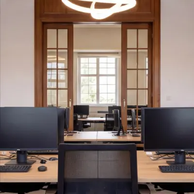 Modern office space rental with ample desks and computers, located at Mauritskade 9 in The Hague Center.
