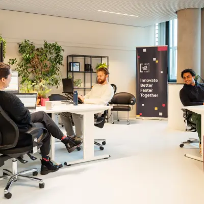 Bright, furnished office space with three people collaborating around desks at Waldopstraat 5, The Hague Center, ideal for office space rental.