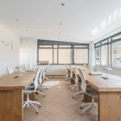 Bright office space with wooden desks and chairs, available for office space rental at Zeestraat 100 in The Hague Center.