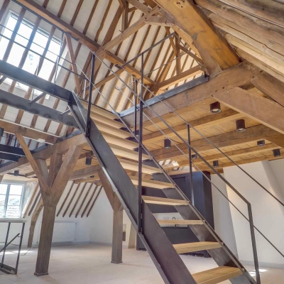 Spacious loft office space featuring exposed wooden beams, skylights, and a modern staircase at Brigittenstraat 22, ideal for rent office space in Utrecht Center.