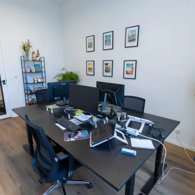 Interior of an office space at Oudegracht 161, Utrecht Center, featuring desks with computers, chairs, and decorative elements on the walls. Ideal for office space rental.