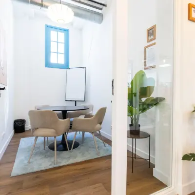 Bright office to rent at Oudegracht 161, Utrecht Center, featuring a small conference table surrounded by modern chairs and a flip chart in a cozy corner.