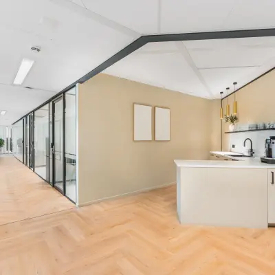 Bright, modern office interior at Leidseveer 2-10, Utrecht Central Station, featuring glass-partitioned workspaces and a kitchenette, available for office space rental.
