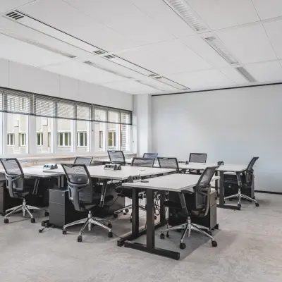 Modern furnished office space with multiple desks and chairs, located at Leidseveer 2-10, Utrecht Central Station, ideal for rent office space. Natural light fills the room through large windows.