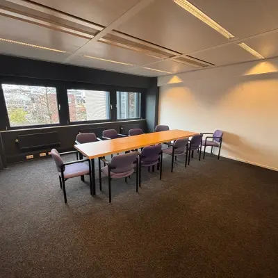Spacious office to rent in Utrecht Kanaleneiland at Bernadottelaan 13 with a large wooden table surrounded by purple chairs, ideal for meetings.