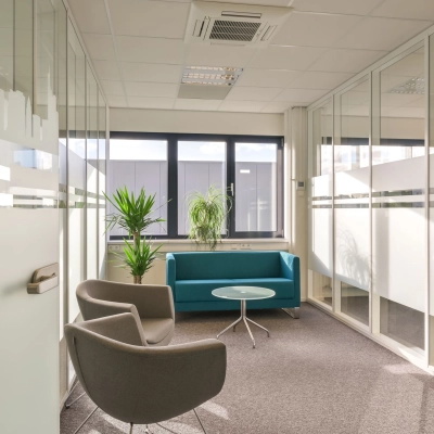 Bright office space with glass walls, a teal couch, and chairs available for rent at Kobaltweg 11, Utrecht Lage Weide.