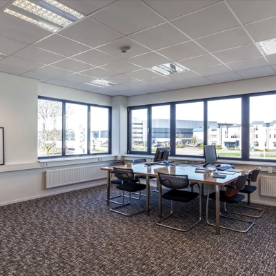 Bright office space with large windows, four desks, computers, and a coat rack in Reactorweg 301, suitable for office space rental in Utrecht Lage Weide.