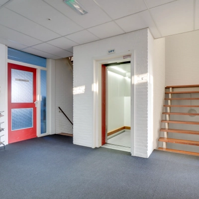 Entrance area of an office building at Zonnebaan 18, Utrecht Lage Weide, featuring a staircase and elevator, ideal for office space rental.