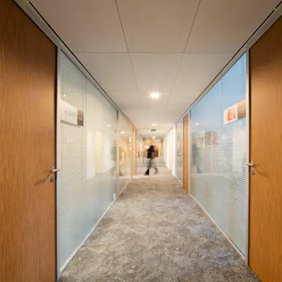Modern hallway in an office at Middenburcht 136, Utrecht Leidsche Rijn, featuring glass doors and subtle lighting.