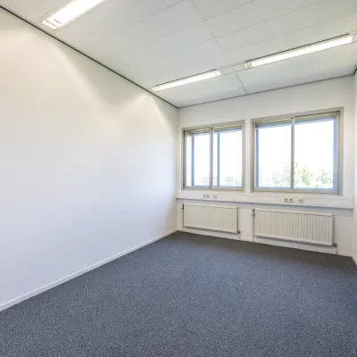 An unfurnished office space with natural light filtering through large windows, located at Goeman Borgesiuslaan 77 in Utrecht North, perfect for office space rental.