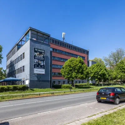 Exterior view of office building at Goeman Borgesiuslaan 77 in Utrecht North, set against a clear sky, with 'te huur' sign visible.