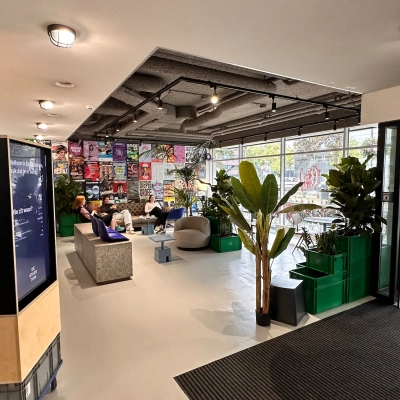Spacious and creatively designed office lounge at Daltonlaan 200, Utrecht Rijnsweerd with modern furnishings and large windows, ideal for office space rental. People are engaged in casual business discussions.