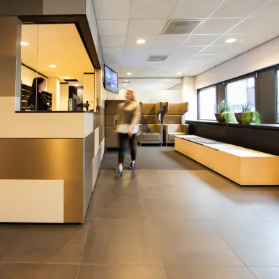 Modern office reception area at Winthontlaan 200, Utrecht South, featuring sleek furnishings and comfortable seating. A person is seen walking through, engaging in business activities.