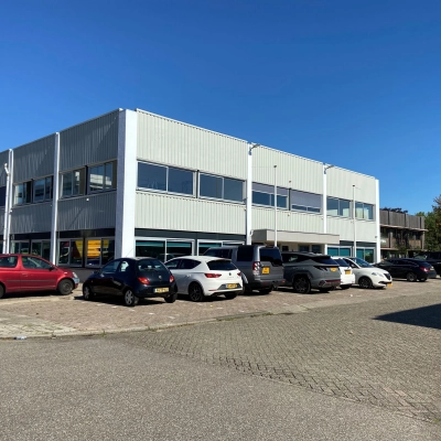 Exterior view of an office building at Zonnebaan 54, Utrecht West, suitable for office space rental. Several cars are parked outside the office to rent.