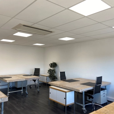 Bright office space with wooden desks and black office chairs at Zonnebaan 54, Utrecht West, ideal for those looking to rent office space. Modern lighting enhances the open, welcoming environment.