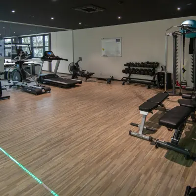 Modern fitness area available for office space rental at Gildestraat 13, Velp, featuring exercise equipment and mirrored walls for an invigorating work environment.