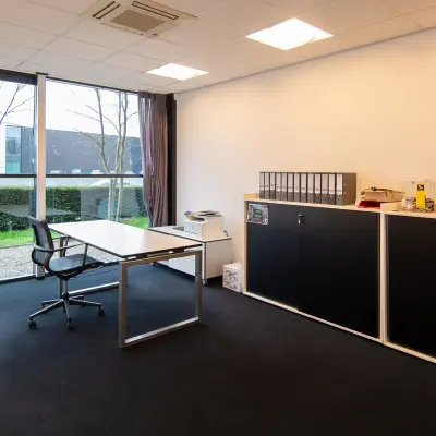 Office space rental at Gildestraat 13, Velp, featuring a bright, furnished workspace with desk, storage units, and large window offering natural light.