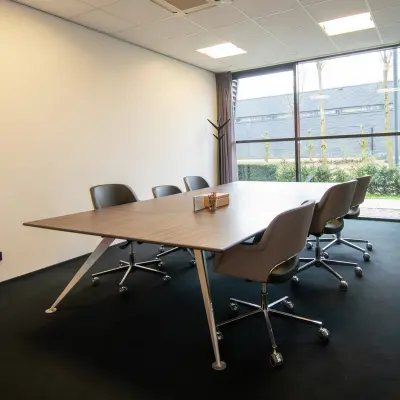 Interior office space at Gildestraat 13, Velp, featuring a modern conference table with chairs, large window, and natural light. Ideal for office space rental seekers.