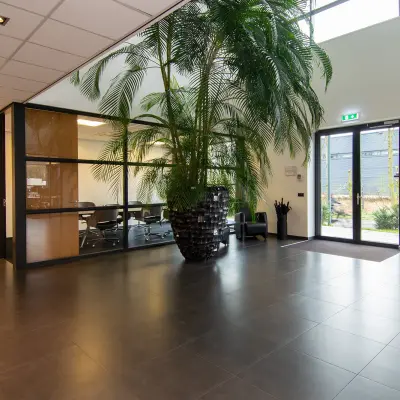 Spacious office entrance at Gildestraat 13, Velp, with a large plant and visible conference room, ideal for office space rental.