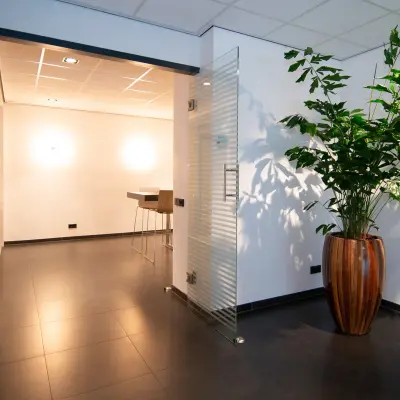 Modern office space at Gildestraat 13, Velp featuring a sleek entrance with glass door and large plant, available for office space rental.