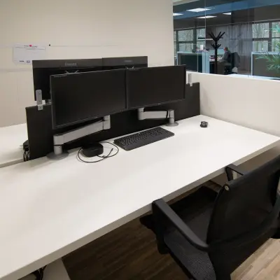 Modern office workspaces available for rent at Gildestraat 13, Velp. The interior features sleek desks with dual monitors, ready for immediate office space rental.