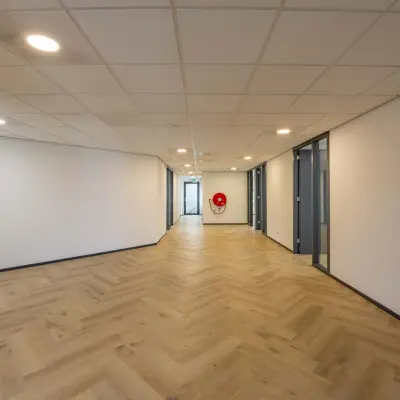 Spacious office hallway with wooden flooring and closed doors, available for office space rental at Keizersveld 47, Venray.