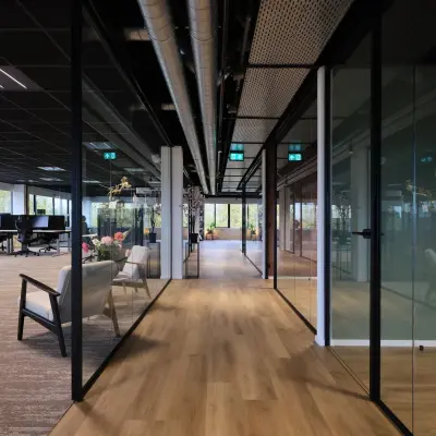 Modern office space with glass partitioned workspaces, featuring comfortable seating and a wooden floor at Havenweg 24, Vianen Utr, ideal for office space rental.