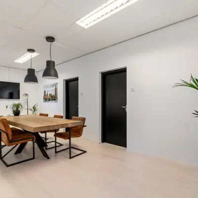 Bright office space at Agro Business Park 22, Wageningen, featuring a meeting table with chairs, plants, and modern lighting. Ideal for companies looking for office space rental.