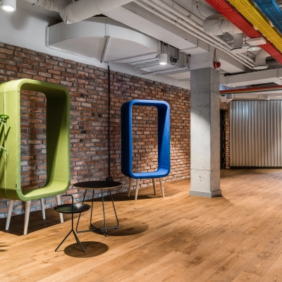Modern office space rental in Warsaw Mokotow with colorful seating and exposed brick walls. Ideal office to rent for creative work environments.
