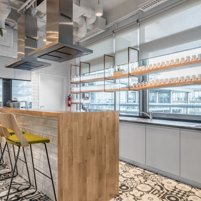 Modern office kitchen at Konstruktorska 11, Warsaw Mokotow, featuring a wooden island and bar stools. Ideal for office space rental.