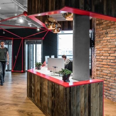 Modern office interior at Konstruktorska 11 in Warsaw Mokotow with a stylish reception desk, industrial-style décor, and a person engaged in business activity.