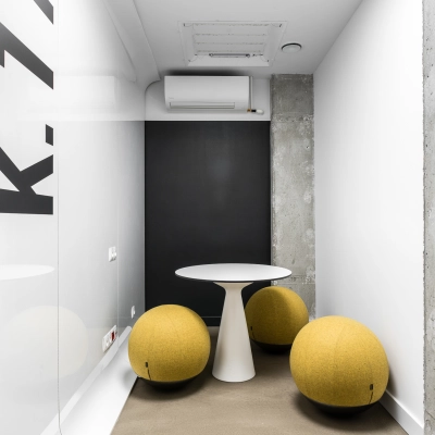 A compact meeting area at Konstruktorska 11 in Warsaw Mokotow with a modern white table and round yellow seats ideal for office space rental.