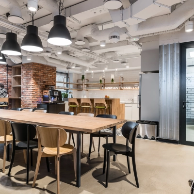 Modern office space at Konstruktorska 11, Warsaw Mokotow with a large wooden table, chairs, and a kitchenette area, ideal for office space rental.