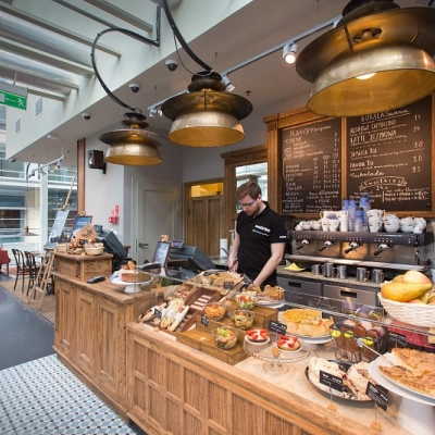 A cozy café area in an office space rental at Postępu 17A, Warsaw Mokotow, featuring a variety of pastries and a barista preparing drinks.