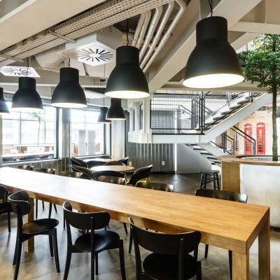 Spacious modern workspace with rows of tables and chairs under stylish lighting, suitable for office space rental in Warsaw Ochota at Al. Jerozolimskie 181B.